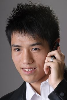 Asian business man using cellphone and smiling, closeup portrait over studio gray background.