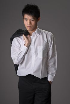 Lonely young man of business put coat on shoulder over studio gray background.