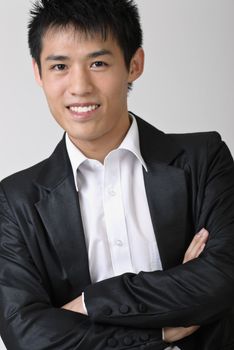 Immature business man of Asian, closeup portrait over studio gray background.