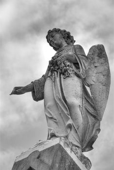 A statue of a mourning angel under moody skies atop a tomb in New Orleans.
