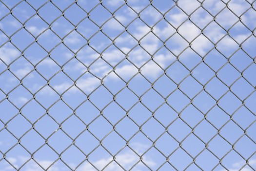 Close up of fence with a blue cloudy sky in the background