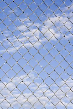 Close up of fence with a blue cloudy sky in the background