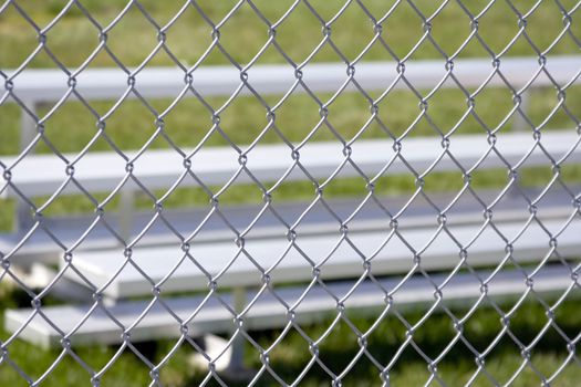 Close up of silver metal sports bleachers shot thru a fence and the fence is in focus the bleachers or blurred 