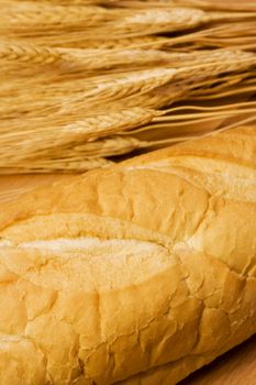 close up of  bread and some wheat on a wood cutting board