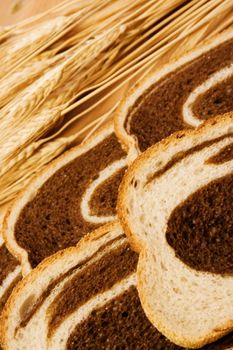 close up of  bread and some wheat on a wood cutting board