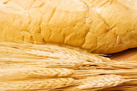 close up of  bread and some wheat on a wood cutting board