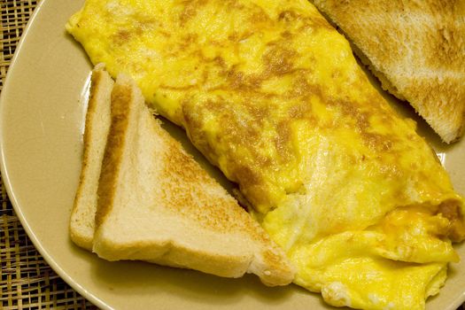 Omelette and white toast on a tan plate on a wicker placemat