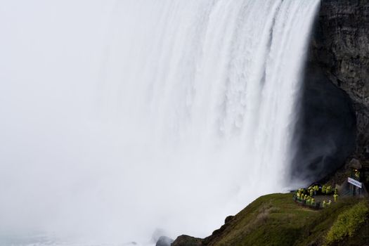 people getting wet next to Niagara falls wearing yellow rain coats