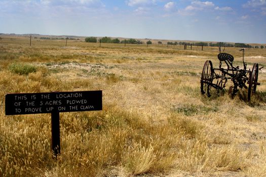 old farm equipment on the prairie with a sign