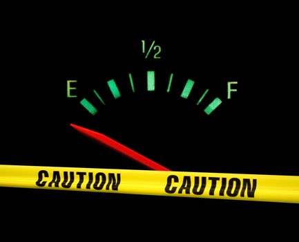 Gas gauge bright colors on empty on a black background with yellow caution tape across the front of it