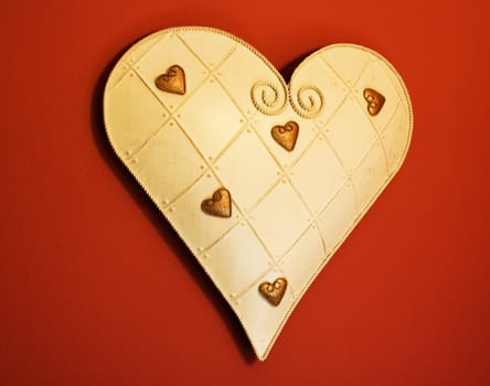 Tin heart with smaller gold hearts hanging on a dark red wall
