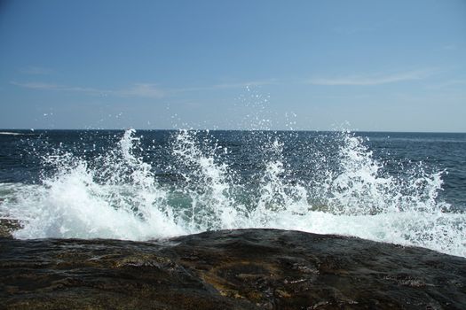 Water splashing against coastal rocks on a sunny day
