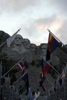 Mt Rushmore at dusk with flags in foreground