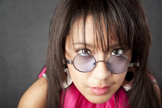 Close up portrait of a pretty brunette woman looking over her glasses