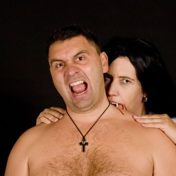 a vampire women bite a screaming man on black