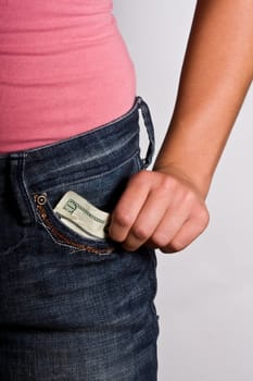 teen girl with money to burn blue jeans and pink shirt stuffing money in front pocket