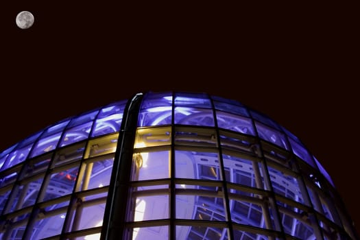 Night shot of glass office building window glass lit with blue purple light room for type above building