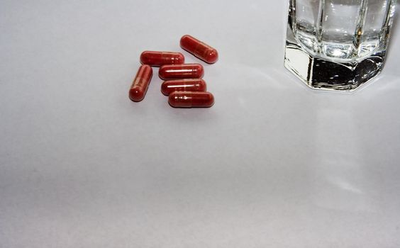 close up of pink pills  with glass of water