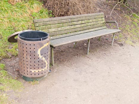 A peaceful bench and rubbish bin in  a park