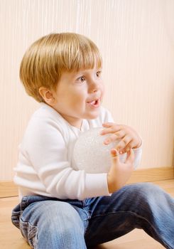The child sitting on the wood floor with white ball