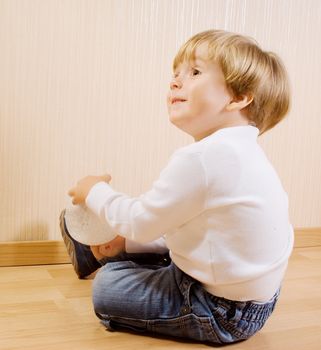 The child playing on the wood floor with white ball
