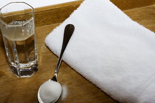 spoon of salt and glass of water on towel and wood serving tray for home healing