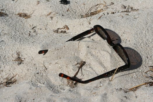 shades sitting in the sand on the beach
