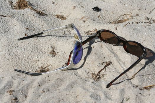 shades sitting in the sand on the beach
