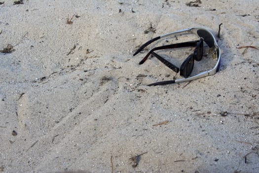 shades sitting in the sand on the beach
