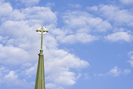 blue cloud filled sky with a cross from a church in the sky