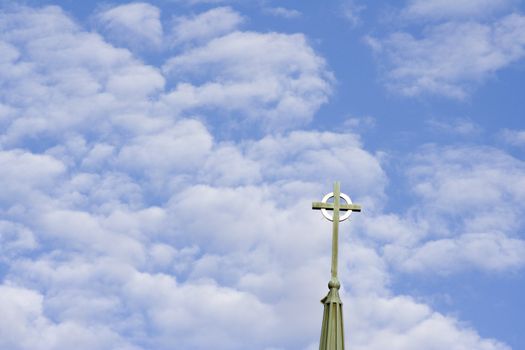 blue cloud filled sky with a cross from a church in the sky