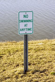 No swimming sign at the edge of a lake overcast day