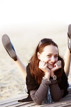 The laughing brunette sits on the wooden bridge at beach