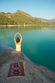 Early morning yoga excecises on the shore of a lake
