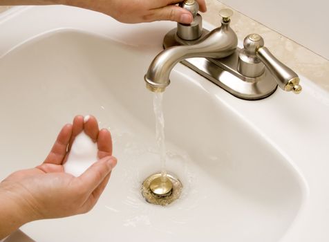 woman washing hand under running water white sink chrome spout