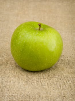 Green apple on the brown sacking background