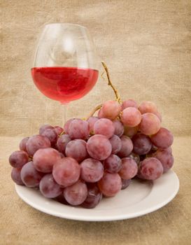Goblet and grapes on plate on the sacking background