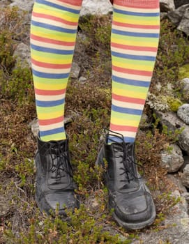 Amusing striped feet in boots against a wood ground