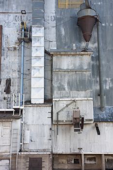 industrial background - a metal exterior of old grain elevator with pipes, ducts, ladders and chutes
