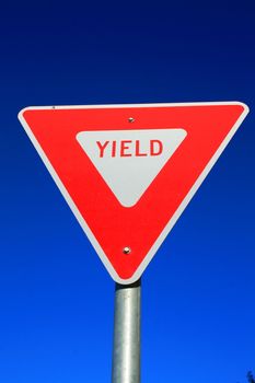 Yield road sign over clear blue sky.
