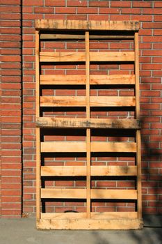 Wooden pallets close up next to a brickwall.
