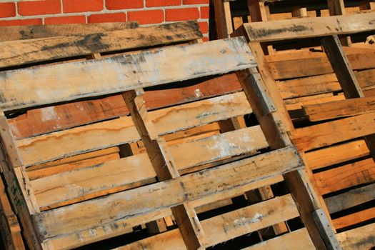 Wooden pallets close up next to a brickwall.
