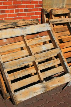 Wooden pallets close up next to a brickwall.
