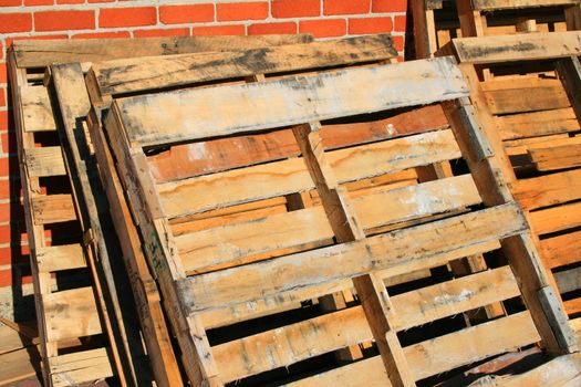 Wooden pallets close up next to a brickwall.
