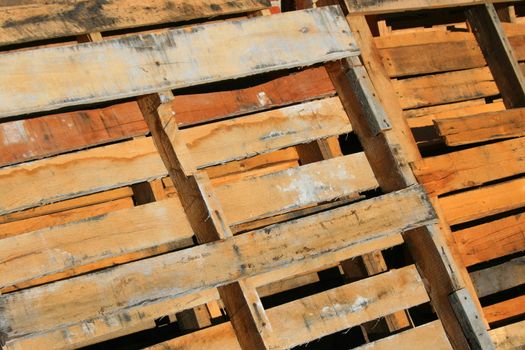 Wooden pallets close up next to a brickwall.
