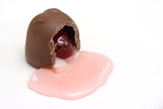A chocolate cherry has been cut open and the syrup is flowing out.