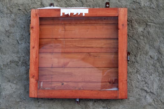 Wooden frame for announcements under glass on concrete wall