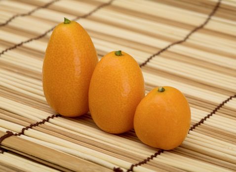 Still-life the three fresh kumquat against a mat