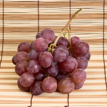 Red grapes on the wooden mat background