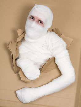 Man in costume mummy looking through hole in cardboard